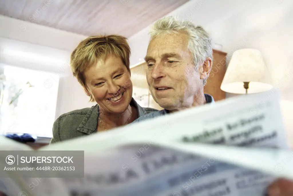 Elderly couple reading newspaper