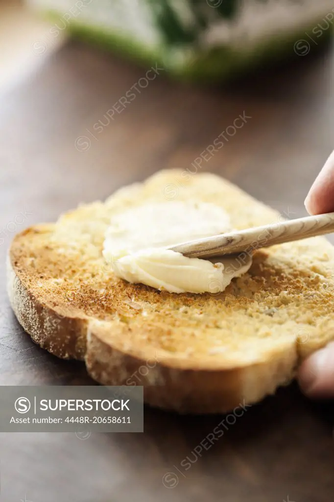 Cropped hand applying butter on bread toast