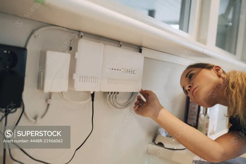 Teenage girl adjusting equipment mounted on wall at home