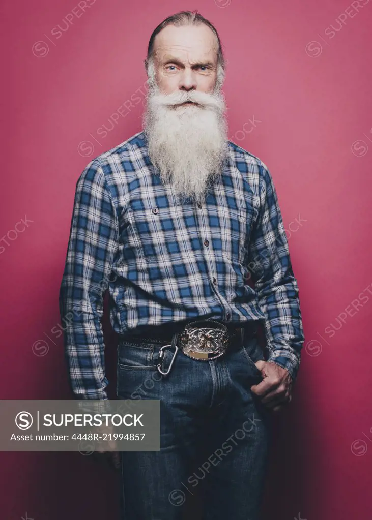 Full length portrait of confident senior man standing against pink background