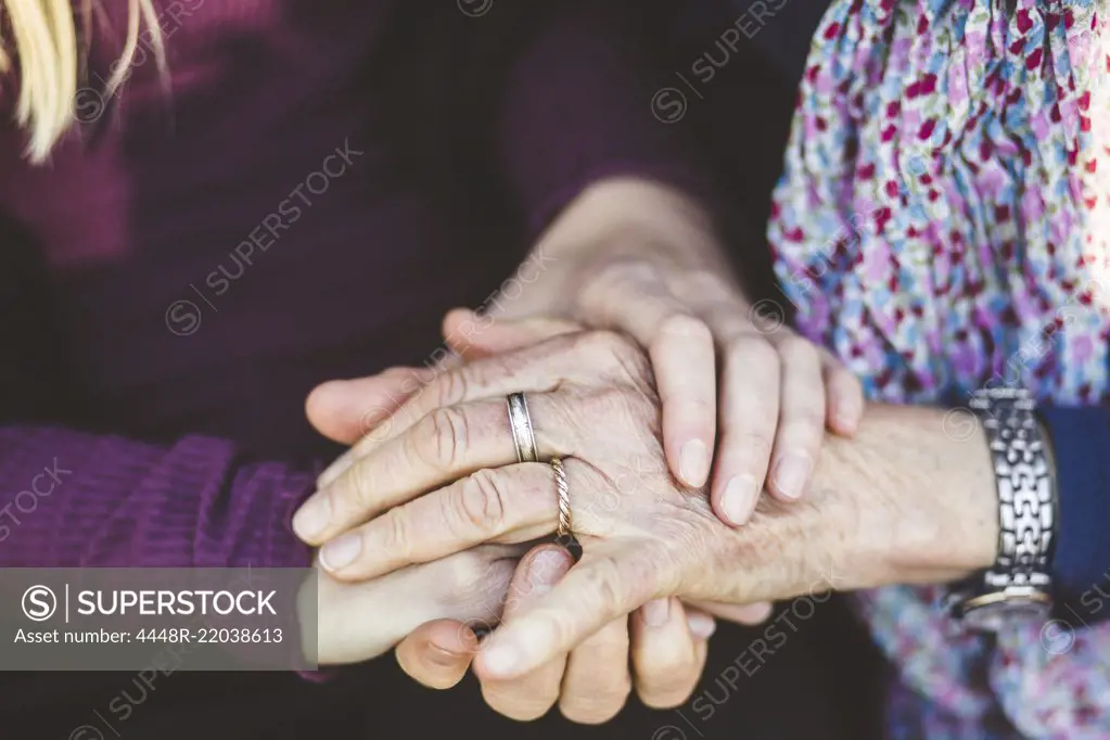 Cropped image of granddaughter and grandmother holding hands