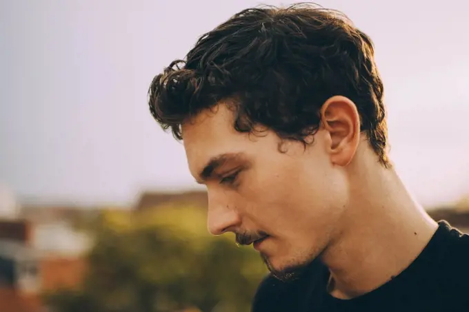 Close-up of thoughtful young man looking down at terrace