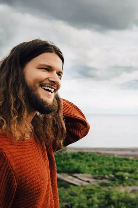 Close-up of smiling man with long hair against beach