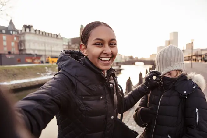 Portrait of happy teenage girl playing mischief with friend in city