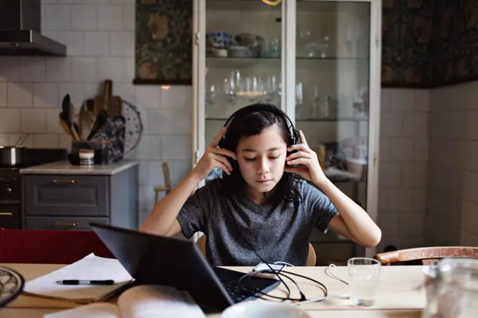 Boy using headphones while doing homework at home
