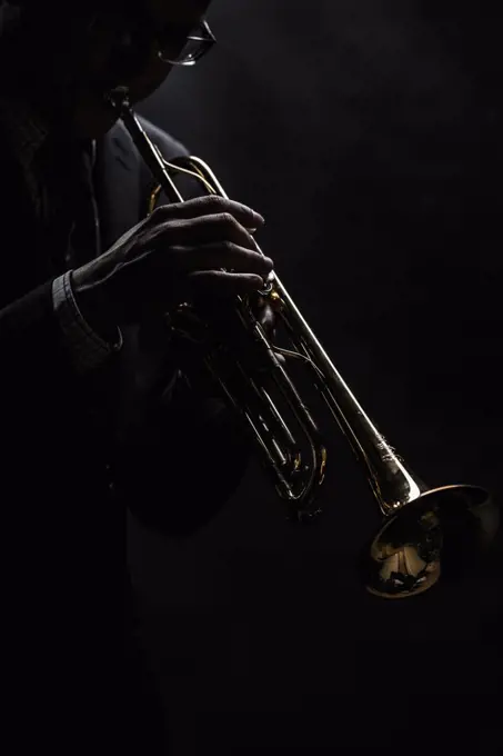 Musician playing trumpet over black background
