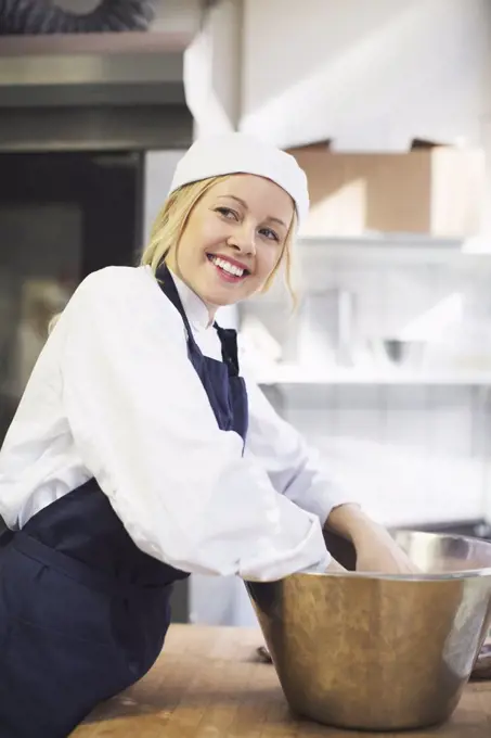 Happy female baker looking away while working in commercial kitchen