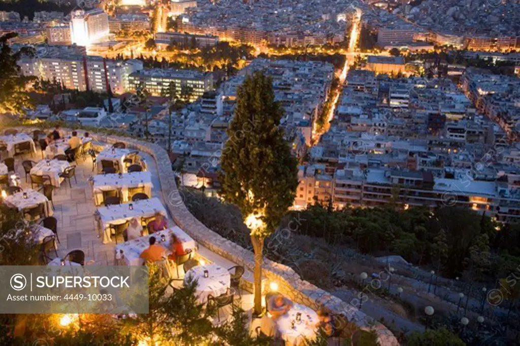 View from the Lykavittos Hill over a restaurant to the ocean of houses of the town at night, Athens, Athens-Piraeus, Greece