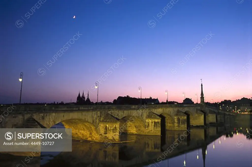 An illuminated stone bridge over the river Loire in the evening, Blois, France