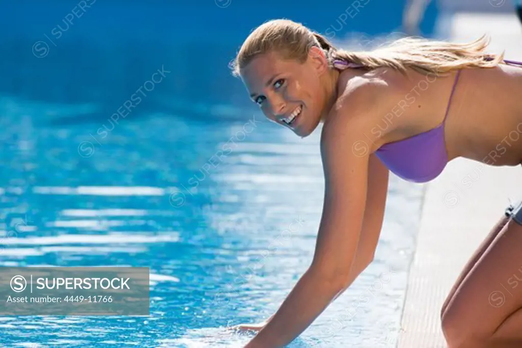 Young woman in bikini refreshing herself at pool, Apulia, Italy