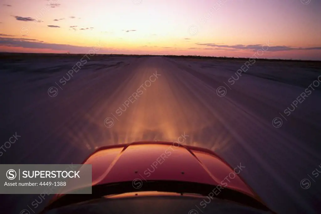 View at the bonnet of a BMW on a dirt road at sunset, Namibia, Africa