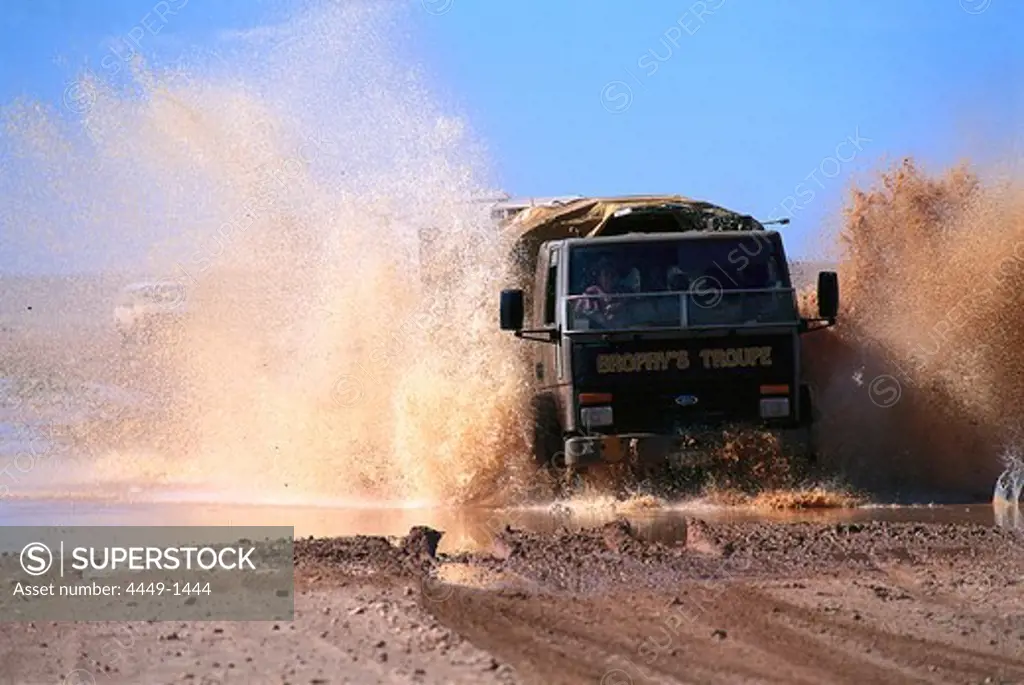 Truck of Fred Brophy's Boxing Troupe driving through water, Outback, Australia