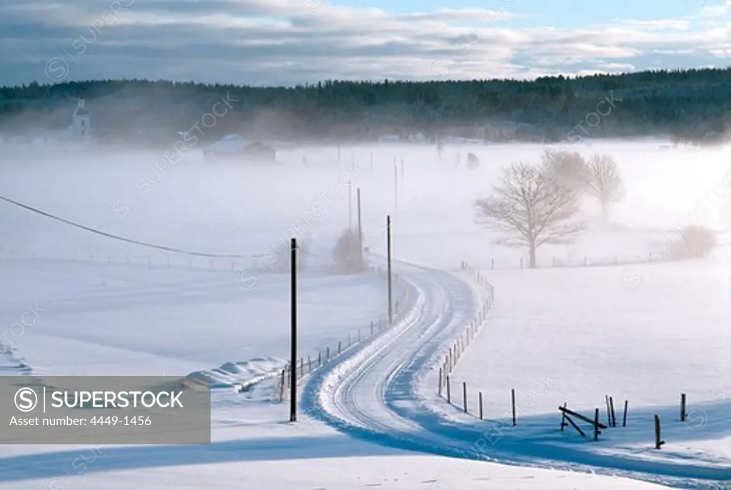 Early morning mist over snow covered country road, Vastergotland, Sweden