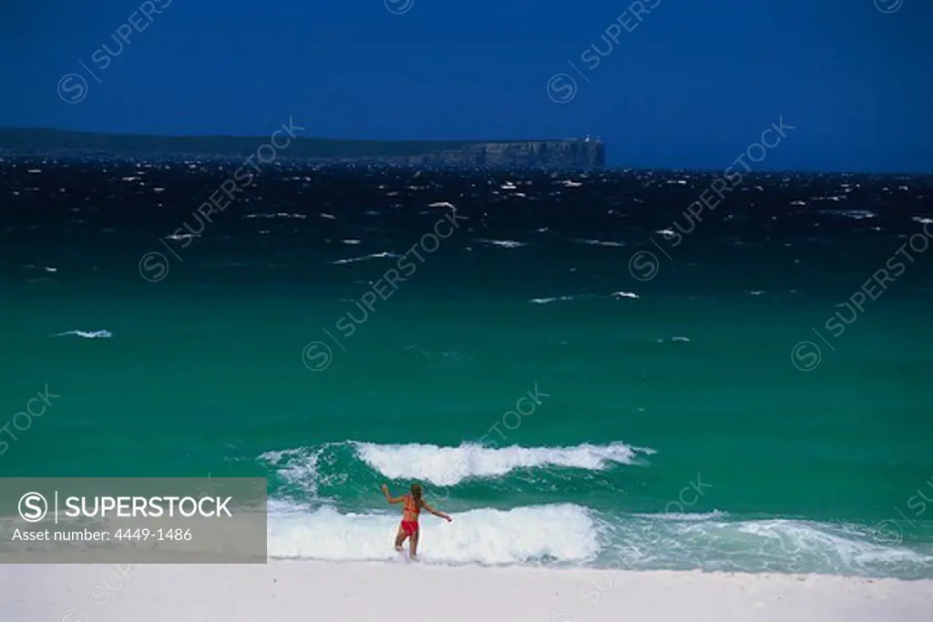 A woman wearing a bikini running into the surge, Hyams Beach, Jervis Bay Marin Park, New South Wales, Australia