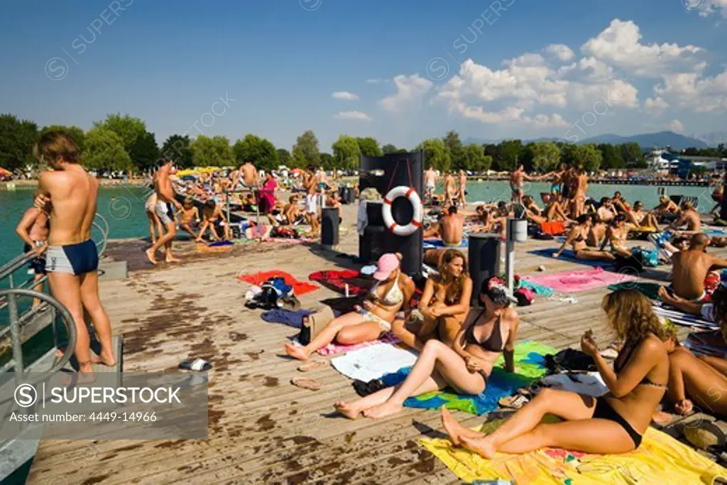 Young people sunbathing on landing stage at Strandbad Klagenfurt, Lake Woerthersee (biggest lake of Carinthia), Klagenfurt, Carinthia, Austria