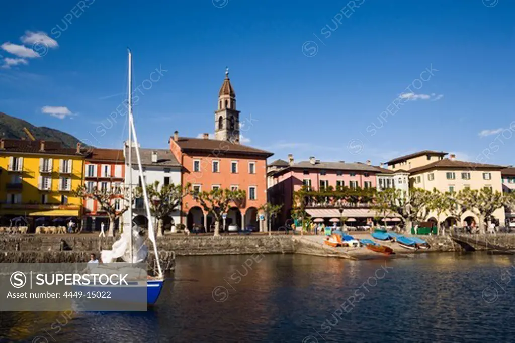 Sailling boat on Lake Maggiore, harbour promenade with spire of church Santi Pietro Paolo in background, Ascona, Ticino, Switzerland