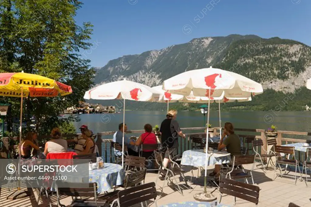 Guests sitting on terrace of a cafe at lake Hallstatt, Hallstatt, Salzkammergut, Upper Austria, Austria