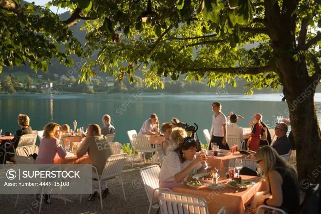 People sitting in the open air area of a restaurant at Lake Fuschl in the evening, Fuschl am See, Salzkammergut, Salzburg, Austria