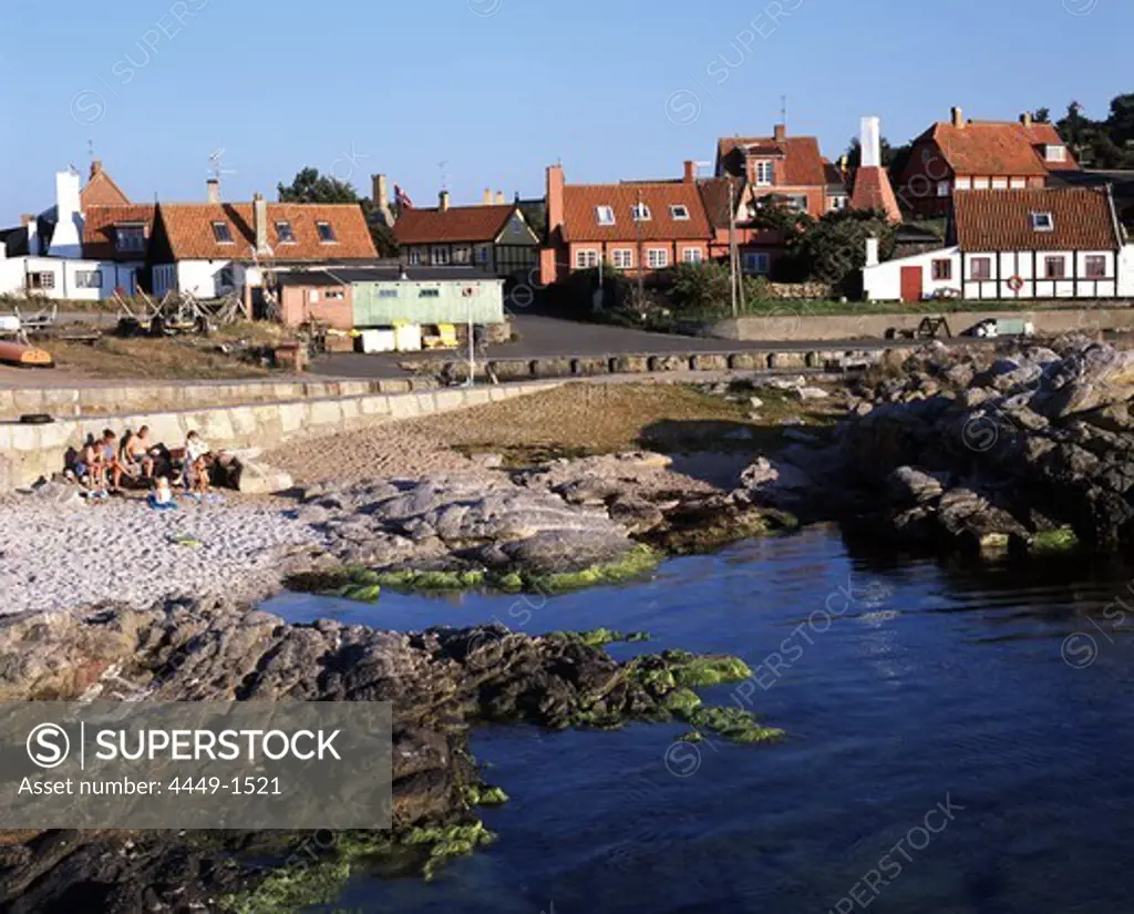People at a pebbled beach and the houses of Gudhejm, North Coast, Bornholm Denmark