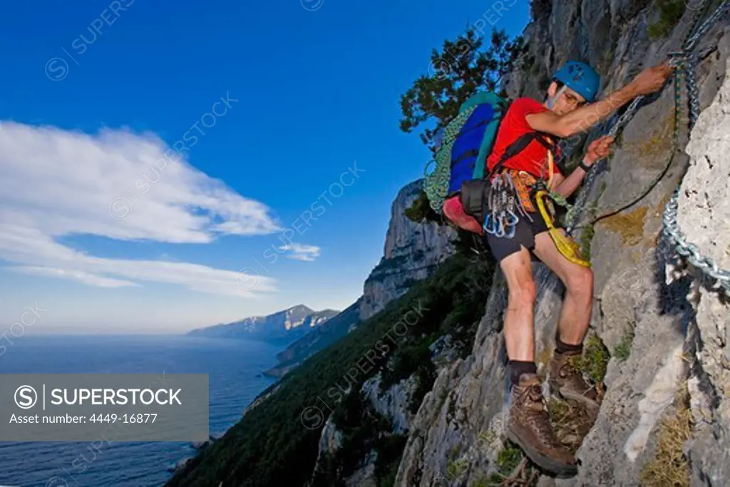 A young men climbs a long a chain, Il Sentiereo Selvaggio Blu, Golfo di Orosei, Sardinia, Italy