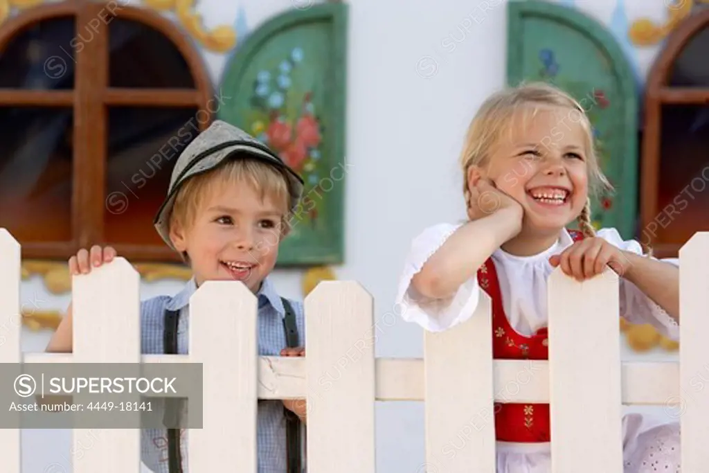 Two children (3-5 years) standing behind a fence