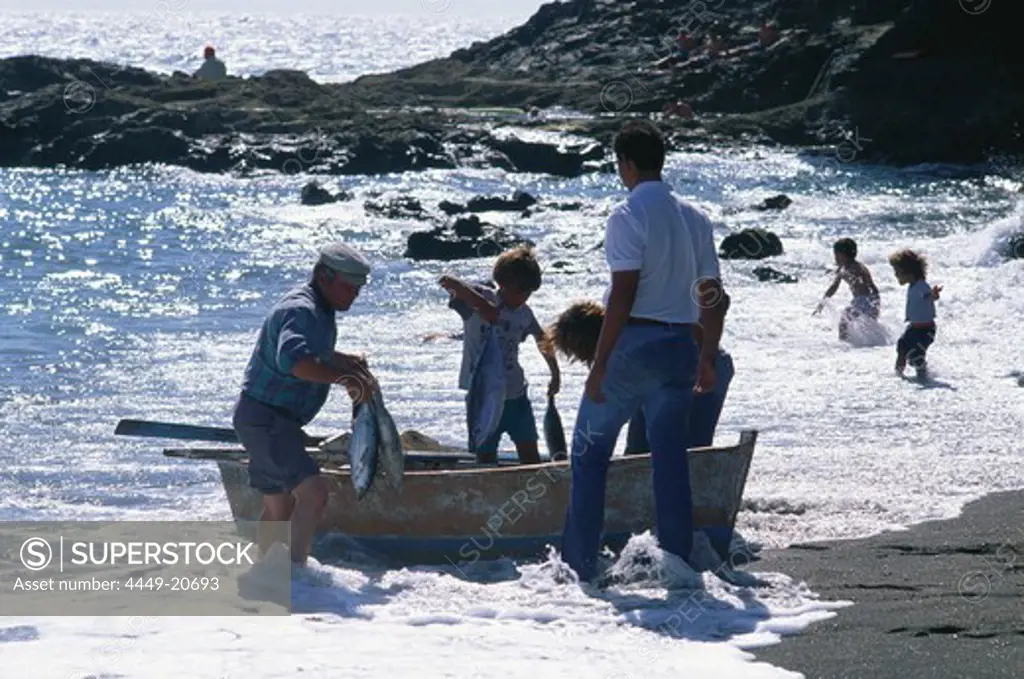 A family of fishermen landing their catch in the surf of the black sand beach of Ajuy, Fuerteventura, Canary Islands, Spain