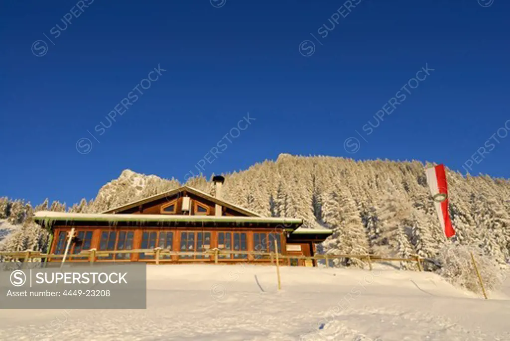 Hut Vorderkaiserfeldenhuette in winter with Tyrolean flag, Zahmer Kaiser, Kaiser range, Kufstein, Tyrol, Austria