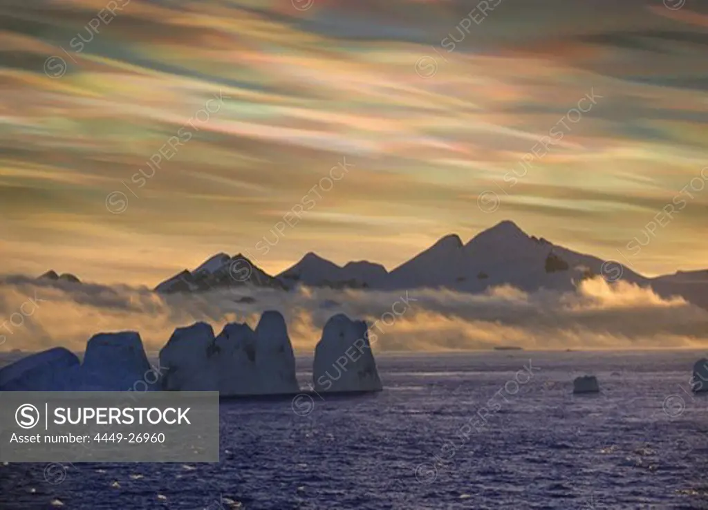 Mother of pearl clouds, nacreous clouds over snow covered iceberg, Antarctic Peninsula, Antarctica