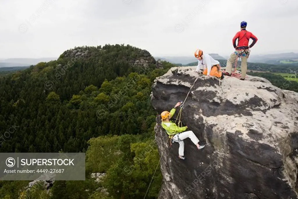 Three young people, a woman and two men rock climbing on sandstone rocks, Papststein, Elbe Sandstone Mountains, Saxon Switzerland, Saxony, Germany