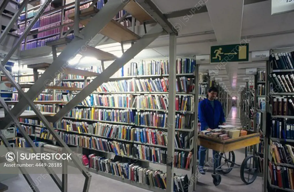 Europe, Germany, Bavaria, Munich, Bavarian State Library, library assistant with a book mobile in a book stack