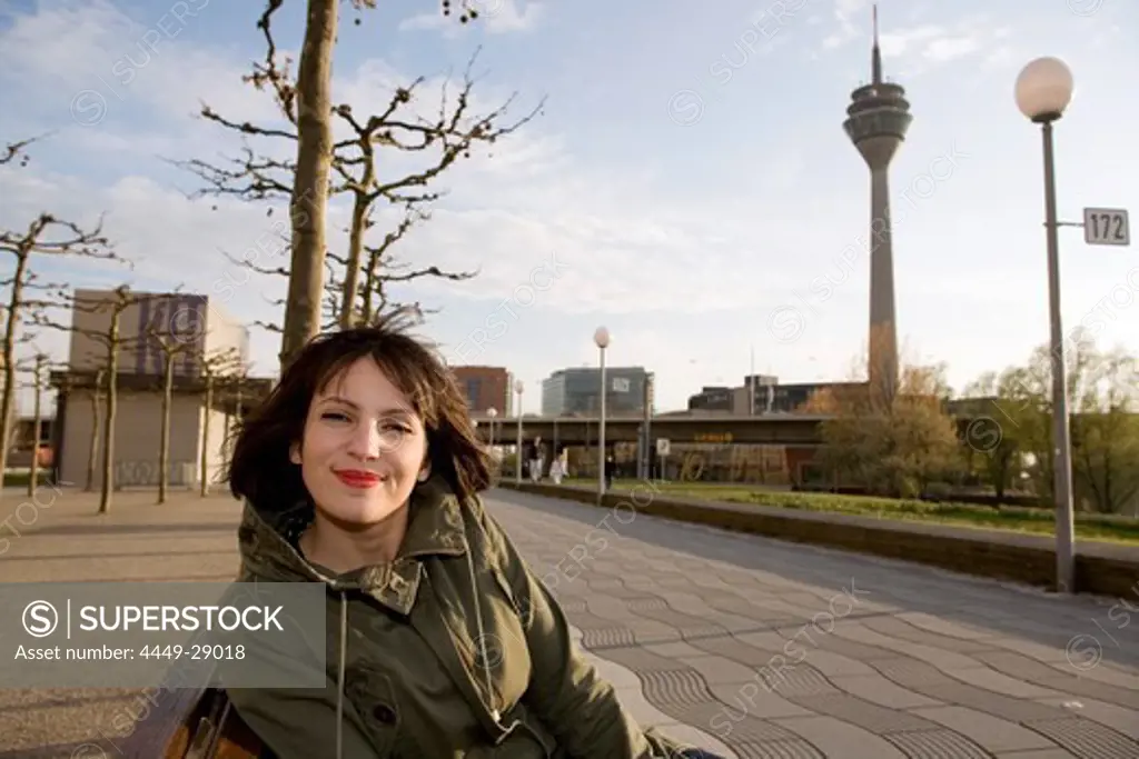 Young woman sitting on a bench at the promenade, Duesseldorf, North Rhine-Westphalia, Germany