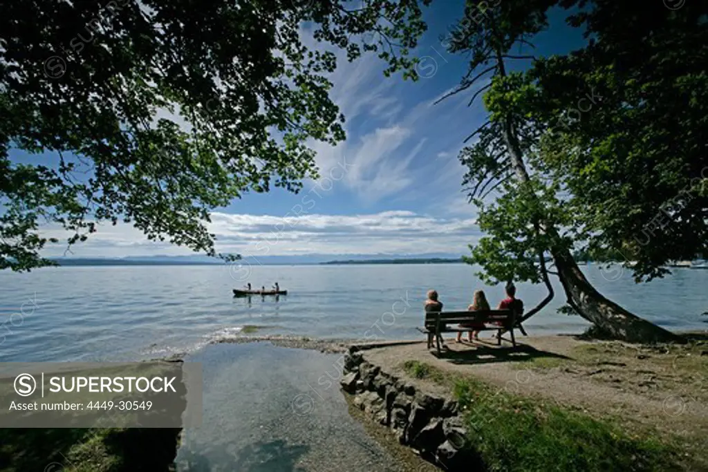 Three people sitting on the lakeshore, kanu in the background, Tutzing, Lake Starnberg, Bavaria, Germany
