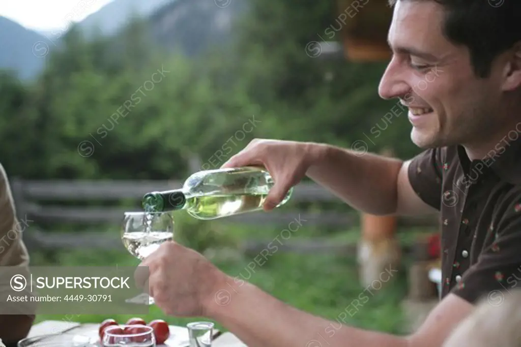 Man pouring wine into glass, National Park Hohe tauern, Kaernten, Austria