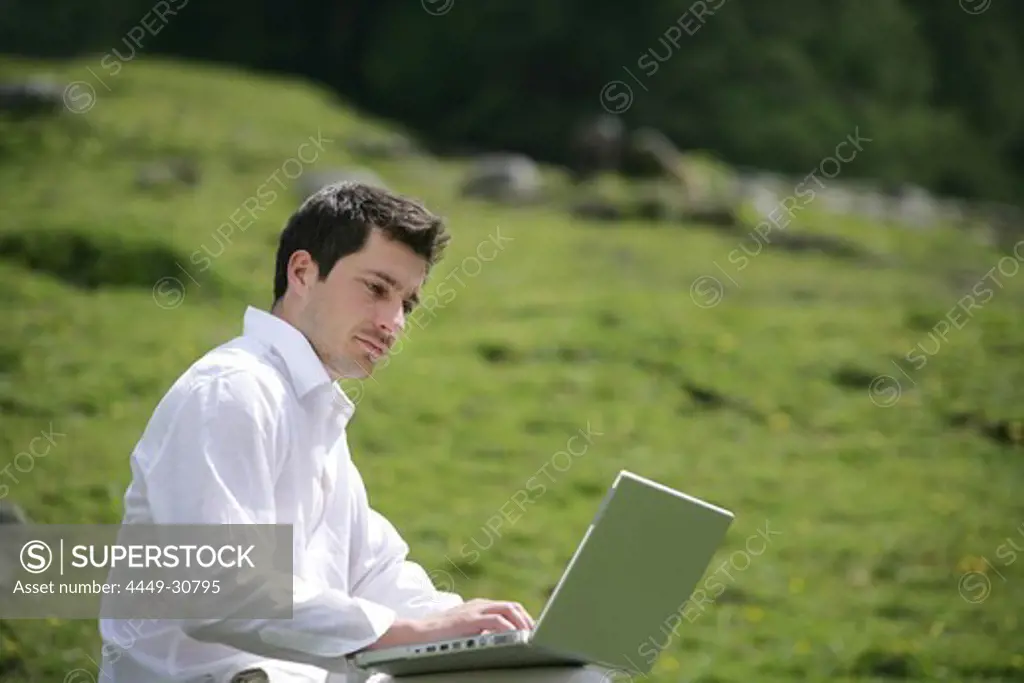 Mid adult man using a laptop, Heiligenblut, Hohe Tauern National Park, Carinthia, Austria