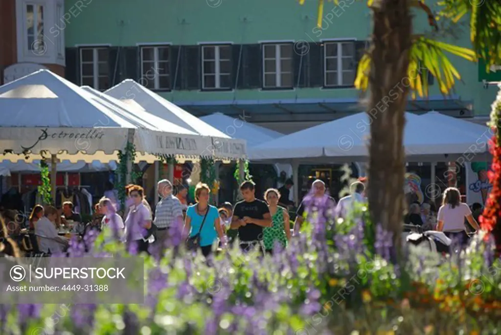 people at main place in city of Lienz, flower decoration out of focus in foreground, pedestrian zone, Lienz, East Tyrol, Austria