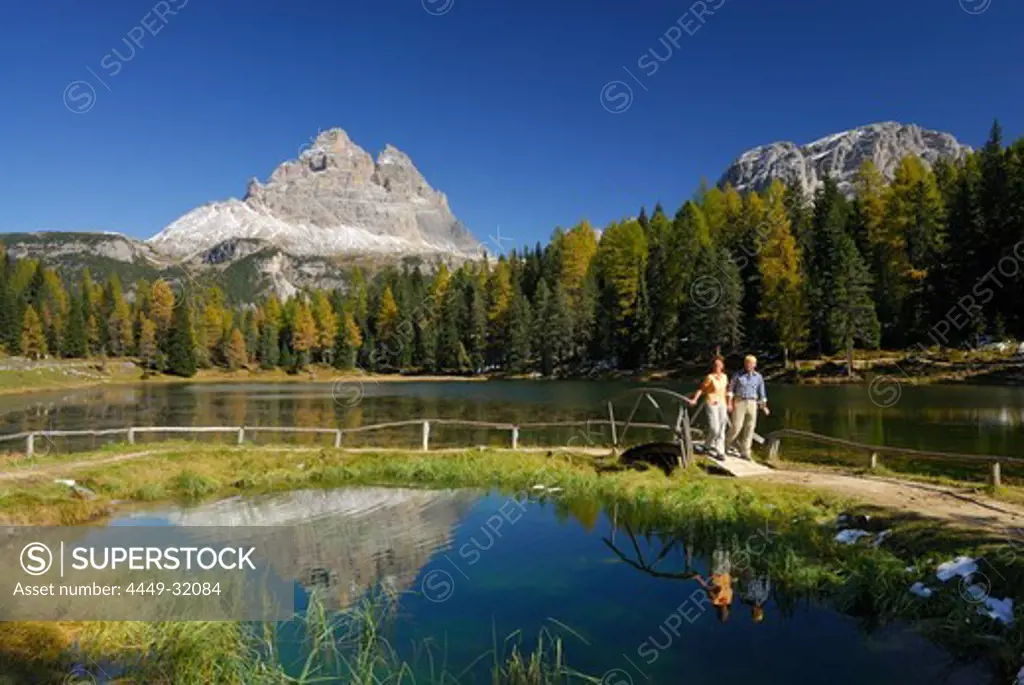 Drei Zinnen above lake Antornosee with couple on path with bridge, Dolomites, South Tyrol, Italy