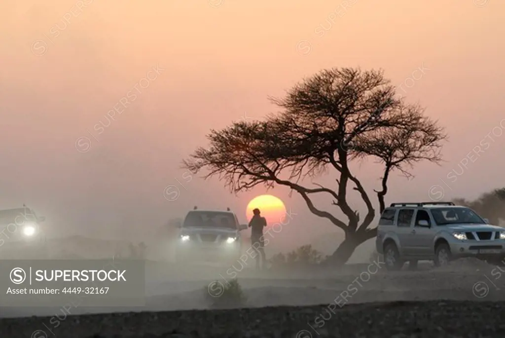 A person and three all-terrain vehicles in front of the setting sun, Al Hajar mountains, Oman, Asia, Oman, Asia