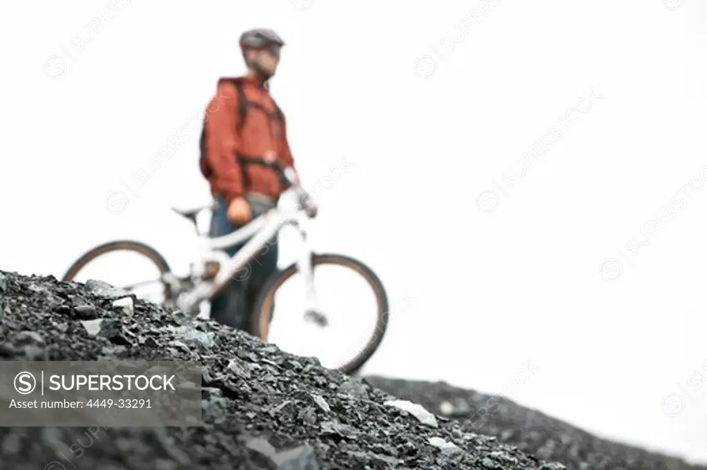 Mountainbiker standing on a scree looking at the view, Ischgl, Tyrol, Austria
