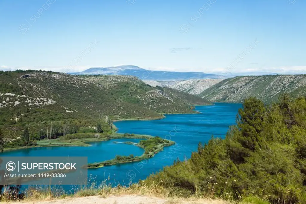 The Krka river and mountain scenery under blue sky, Krka National Park, Dalmatia, Croatia, Europe