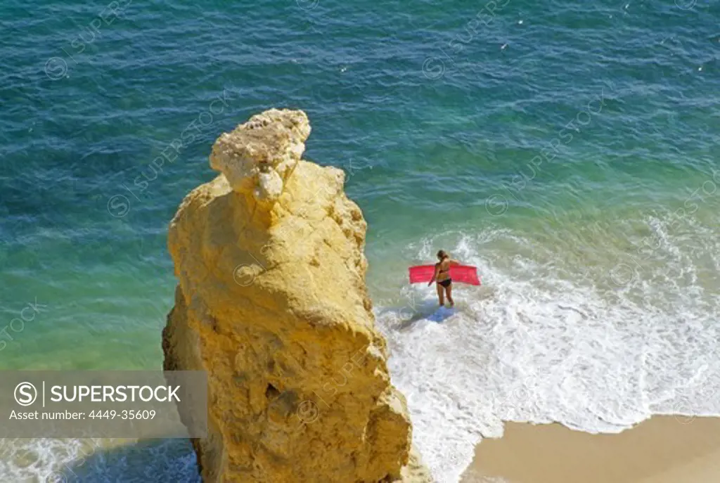 View at beach and a woman with air mattress on the waterfront, Praia da Marinha, Algarve, Portugal, Europe