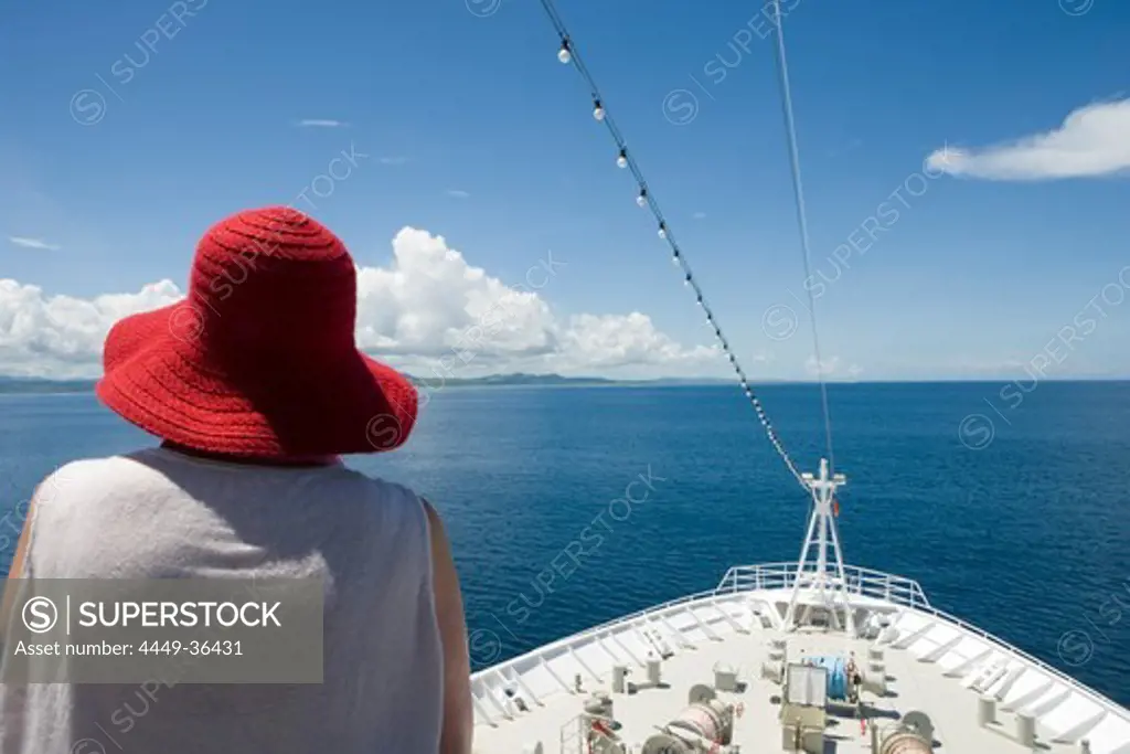 Woman wearing red hat and bow of MV Columbus in the sunlight, Mamanuca Archipelago, Fiji Islands, South Pacific, Oceania