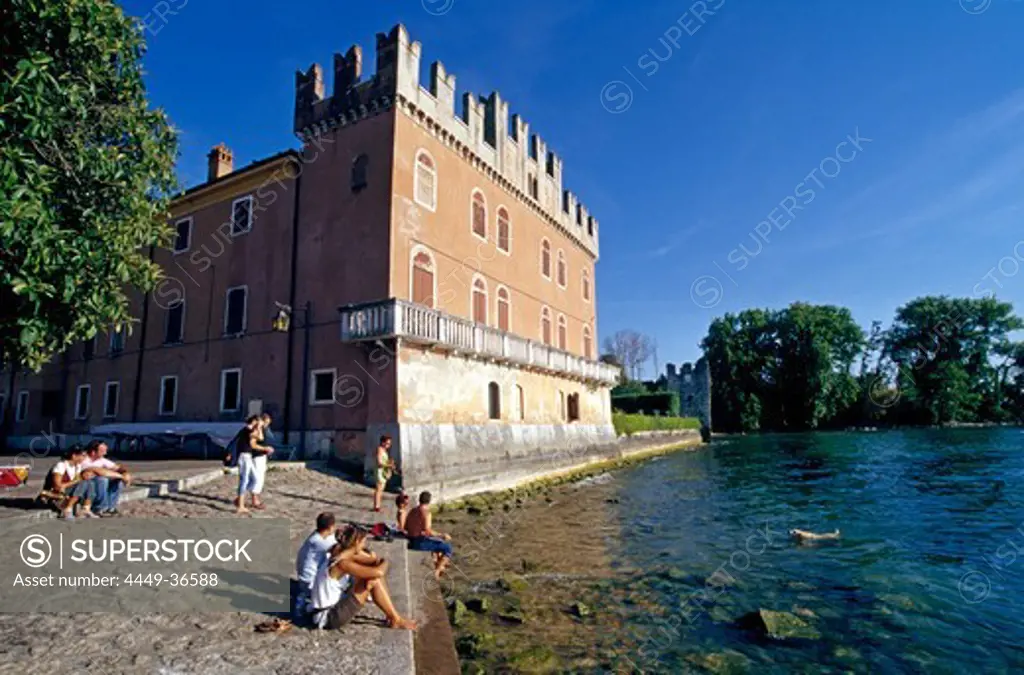 People sitting at the lakeside at the Scaliger castle, Lazise, Lake Garda, Veneto, Italy, Europe