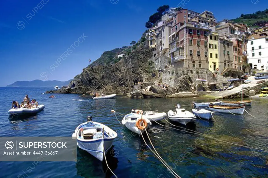 Rubber dingi and fishing boats at harbour under blue sky, Riomaggiore, Cinque Terre, Liguria, Italian Riviera, Italy, Europe