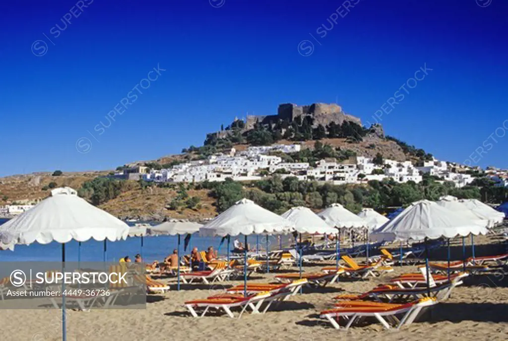 View at bay with beach, city and acropolis under blue sky, Lindos, Island of Rhodes, Greece, Europe