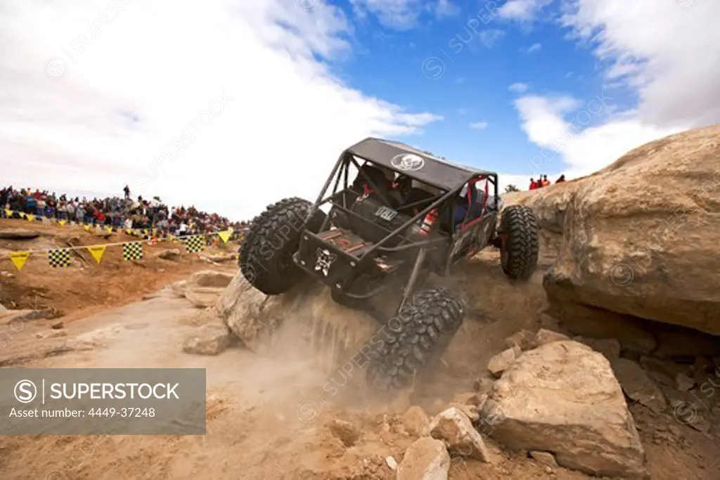 View towards a racing car which is driving over a rock at the Rock Crawling Race, Rock Crawling, Moab, Utah, USA