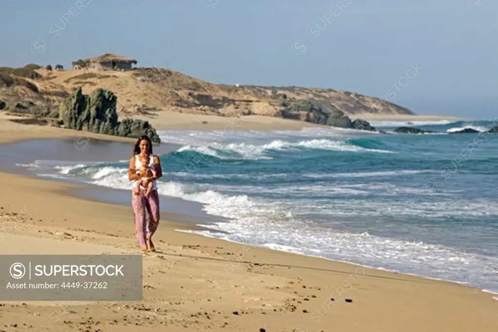 Woman walking along the beach holding her 5 month old baby, Nine Palms, Baja California Sur, Mexico