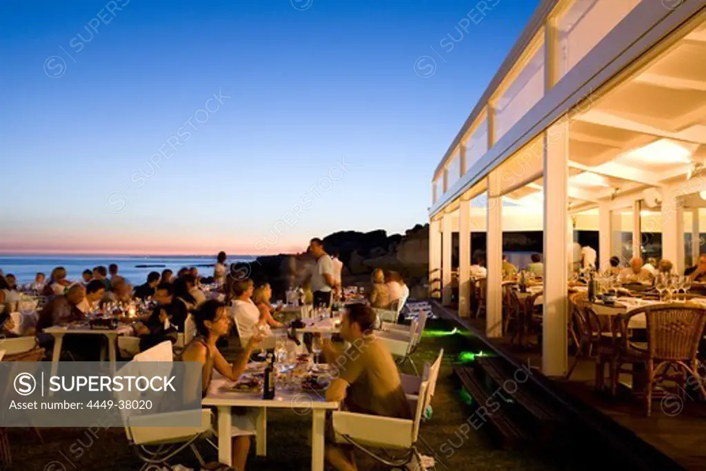 Tourists dining in a fish Restaurant on the beach at sunset, Praia do Evaristo, Albufeira, Algarve, Portugal