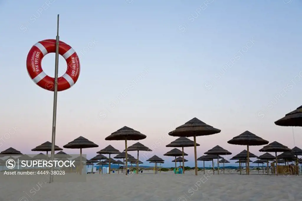 Life ring and beach huts on the beach at dawn, Ilhe de Tavira, Tavira, Algarve, Portugal
