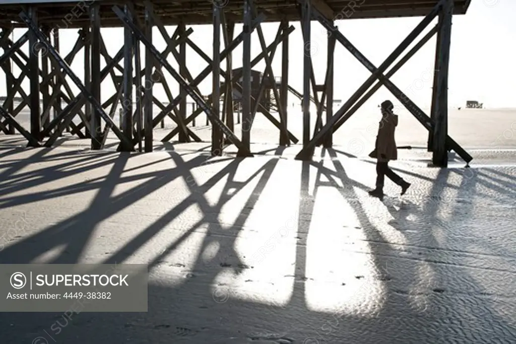 Woman passing stilt house at beach, St Peter Ording, Wadden Sea National Park, Schleswig-Holstein, Germany