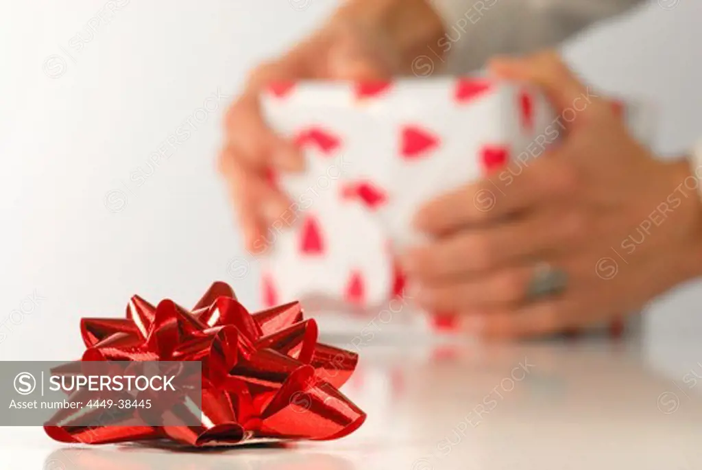 Red bow with person packing gift in background